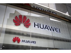 FILE - In this Jan. 29, 2019, file photo, the logos of Huawei are displayed at its retail shop window reflecting the Ministry of Foreign Affairs office in Beijing. China's Huawei is set to take the wraps off a new folding-screen phone, in a fresh bid for global dominance of the stagnating smartphone market. The company is expected on Sunday, Feb. 24, 2019 to unveil the new device, which can be used on superfast next-generation mobile networks due to come online in the coming years.