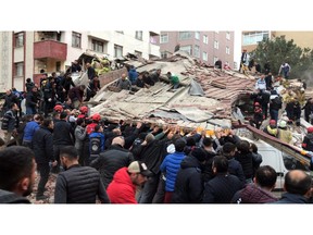 Rescue workers and people try to remove debris of a seven-story building which collapsed in Istanbul, Wednesday, Feb. 6, 2019. A seven-story building collapsed in Istanbul on Wednesday, killing at least one person and trapping several others inside the rubble, Turkish media reports said. (DHA via AP)