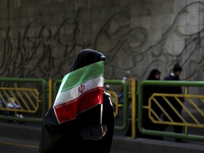 FILE - In this Feb. 11, 2016 file photograph, an Iranian woman holds the national flag during a rally commemorating the 37th anniversary of the Islamic revolution, in Tehran, Iran. Iran's 1979 Islamic Revolution initially inspired both Islamic militants and Islamists across the Mideast. They saw the revolution as the starting gun in a competition to push out the strongman Arab nationalism that had taken hold across the Middle East. However, analysts say Iran's push to back militants in the wider Mideast and Saudi Arabia's efforts to mobilize the Sunni world against the Shiite power would turn many away.