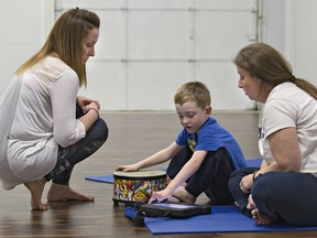 Yoga instructor Trish Leblanc watches as seven year old Bennett Cochrane, sitting with his mother Renee, communicates using a tablet on Wednesday May 20, 2015.