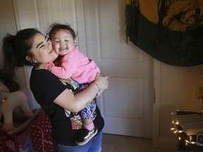 Seanna Leilani Chavez, left, holds Athena Chavez, 2, the sister and daughter of Aaron Francisco Chavez respectively, as the two stand next to a shrine for Aaron at the family home Wednesday, Feb. 6, 2019, in Tucson, Ariz. Aaron Chavez died of a fentanyl overdose at the age of 19.