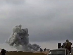 This frame grab from video provided on Tuesday, Feb. 12, 2019, by the Syrian Observatory for Human Rights, an opposition group, that is consistent with independent AP reporting, shows U.S.-backed Syrian Democratic Forces fighters looking at smoke rising from a shell that targeted Islamic State group militants, in the village of Baghouz, Deir El-Zour, eastern Syria. Fighting between U.S.-backed fighters and IS inflicted more casualties among people fleeing the violence in eastern Syria Tuesday where the extremists are on the verge of losing the last area they control. (Syrian Observatory for Human Rights via AP)