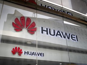 FILE - In this Jan. 29, 2019, file photo, the logos of Huawei are displayed at its retail shop window reflecting the Ministry of Foreign Affairs office in Beijing. China says neither the U.S. nor its allies have come up with any conclusive evidence that Chinese telecommunications equipment maker Huawei is a threat to their national security.