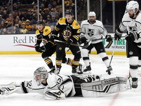 Los Angeles Kings goaltender Jonathan Quick dives after a loose puck as Boston Bruins' Danton Heinen (43) looks on during the second period of an NHL hockey game Saturday, Feb. 9, 2019, in Boston.