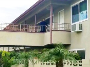 In this still image taken from video, an investigator is seen at the apartment building where authorities say a mother threw her young son from a second-story apartment landing and jumped herself as police arrived in Upland, Calif., Tuesday, Feb. 26, 2019. The mother and 1-year-old boy were hospitalized in stable condition, police said. A baby girl was found dead inside their apartment.