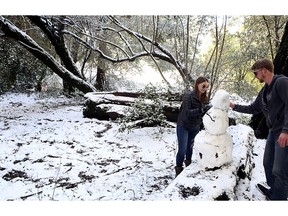 Sarah Fisher, left, and Patrick LaBarre play in the snow near the intersection of Empire Grade and Alba Road in Bonny Doon, Calif., in Santa Cruz County, Tuesday, Feb. 5, 2019. Snow, ice and shivering cold blasted normally mild cities from Seattle to Las Vegas to San Francisco on Tuesday as winter weather sweeping across the U.S. West shuttered schools, made travel treacherous and closed all roads in Yosemite National Park.