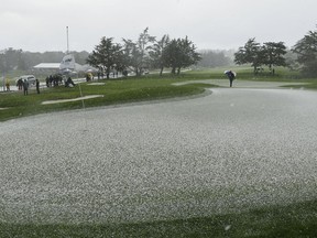 Hail covers the second green of the Pebble Beach Golf Links as a rules official looks on during the final round of the AT&T Pebble Beach Pro-Am golf tournament Sunday, Feb. 10, 2019, in Pebble Beach, Calif. Play was suspended after the hailstorm.