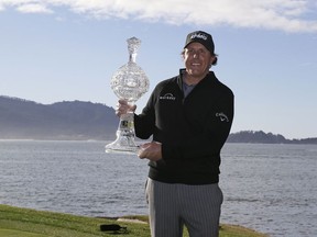 Phil Mickelson poses with his trophy on the 18th green of the Pebble Beach Golf Links after winning the AT&T Pebble Beach Pro-Am golf tournament Monday, Feb. 11, 2019, in Pebble Beach, Calif.