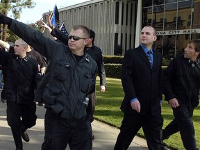 FILE-In this Saturday, Nov. 5, 2011 fule photo, Jeff Schoep, second right in business suit, commander of the National Socialist Movement, leave under police protection after a rally against illegal immigration in Pomona, Calif. One of the largest and oldest neo-Nazi groups in the U.S. appears to have an unlikely new leader: James Stern, a black activist who has vowed to dismantle it. Michigan corporate records indicate Stern replaced Jeff Schoep as the Detroit-based group's leader in January. Stern and Schoep didn't respond to requests for comment.