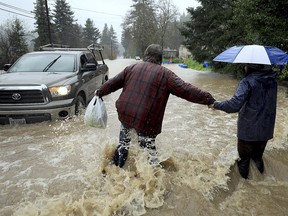 Residents along Armstrong Woods Road head back to their home after the road became impassable to most vehicles, Tuesday, Feb. 26, 2019 in Guerneville, Calif. Thousands of people along a flooded river were under evacuation orders Wednesday as a relentless storm pounded Northern California, drenching the San Francisco Bay Area and pummeling the Sierra Nevada with snow.
