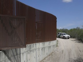 FILE - In this Aug. 11, 2017, file photo, a U.S. Customs and Border Patrol vehicle passes along a section of border levee wall in Hidalgo, Texas. The U.S. government is preparing to begin construction of more border walls and fencing in South Texas' Rio Grande Valley, likely on federally-owned land set aside as wildlife refuge property. Heavy construction equipment is supposed to arrive starting Monday. A photo posted by the nonprofit National Butterfly Center shows an excavator parked on its property.