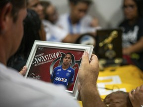 A man looks at a photo of the late Christian Esmerio Candido during his burial at a cemetery in Rio de Janeiro, Brazil, Sunday, Feb. 10, 2019. Hundreds of grief-stricken people attended the funeral of the 15-year-old, one of 10 young soccer players killed in a fire at the training ground of Brazilian soccer club Flamengo on Friday.
