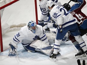 Toronto Maple Leafs goaltender Frederik Andersen, left, sits on the puck after stopping a shot off the stick of Colorado Avalanche left wing A.J. Greer, back right, as Toronto defenseman Nikita Zaitsev covers in the first period of an NHL hockey game, Tuesday, Feb. 12, 2019, in Denver.