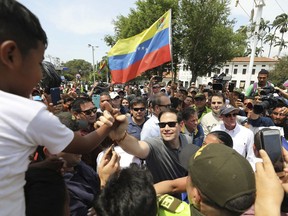 U.S. Senator Marco Rubio, R-Fla., greets Venezuelan migrants near the Simon Bolivar International Bridge, which connects Colombia with Venezuela, where one holds up Venezuelan flag in La Parada, near Cucuta, Colombia, Sunday, Feb. 17, 2019. As part of U.S. humanitarian aid to Venezuela, Rubio is visiting the area where the medical supplies, medicine and food aid is stored before it it expected to be taken across the border on Feb. 23.
