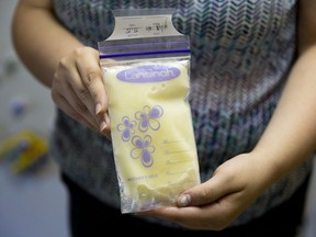 A woman poses for a photograph with her frozen breast milk Wednesday, June 17, 2015, in West Chester, Pa. A new study offers possible clues to why babies who drink pumped breast milk are at greater risk of asthma, allergies and obesity than those who get breastmilk straight from the breast.