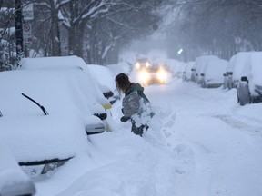 A woman digs her car out of a snowbank during a winter storm in Montreal on Wednesday, February 13, 2019. It's a decision that sparks joy for some, and chaos for others: The snow day. Wintry conditions have forced multiple school closures across the country in recent weeks, with some regions recording an unusually high number of snow days.
