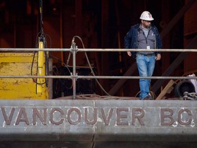A Seaspan Vancouver Shipyards worker stands on a barge under construction during a party in celebration of the company being awarded an $8-billion federal shipbuilding contract in North Vancouver, B.C., on Wednesday November 2, 2011. In a move that will likely send shockwaves through Quebec and its shipbuilding industry, the federal government is planning to speed up construction of two permanent support vessels for the navy.