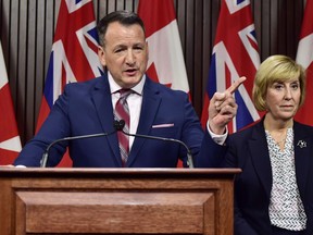 Ontario's Energy Minister Greg Rickford speaks as Labour Minister Laurie Scott looks on during a press conference at Queen's Park in Toronto on Monday, Dec. 17, 2018. Ontario's energy minister says the government will take "any and all action necessary" if Hydro One doesn't drastically cut its proposed CEO compensation, but the semi-private utility appears not to be budging.