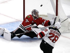 Chicago Blackhawks goalie Cam Ward, left, cannot stop a goal by New Jersey Devils defenseman Damon Severson, right, during the first period of an NHL hockey game Thursday, Feb. 14, 2019, in Chicago.