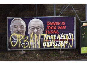 A billboard from a campaign of the Hungarian government showing EU Commission President Jean-Claude Juncker and Hungarian-American financier George Soros with the caption "You, too, have a right to know what Brussels is preparing to do." is displayed at a street in Budapest, Hungary, Feb. 26, 2019. The Hungarian government claims that EU leaders like Juncker, backed by Soros, want to bring mass migration into Europe. The billboard has been sprayed with graffiti saying "Orban thief," in reference to Hungarian Prime Minister Viktor Orban.