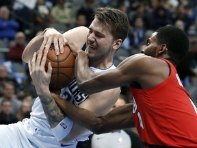 Dallas Mavericks forward Luka Doncic (77) and Portland Trail Blazers forward Maurice Harkless (4) wrestle for control of the ball in the first half of an NBA basketball game in Dallas, Sunday, Feb. 10, 2019.