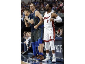 Dallas Mavericks forward Dirk Nowitzki, left, and Miami Heat guard Dwyane Wade, right, prepare to enter during the first half of an NBA basketball game in Dallas, Wednesday, Feb. 13, 2019.