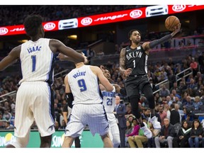 Brooklyn Nets guard D'Angelo Russell (1) lays the ball up in front of Orlando Magic forward Jonathan Isaac (1) and center Nikola Vucevic (9) during the first half of an NBA basketball game in Orlando, Fla., Saturday, Feb. 2, 2019.