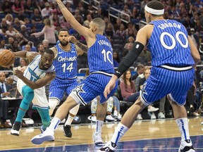 Charlotte Hornets guard Kemba Walker (15) dribbles against Orlando Magic guard D.J. Augustin (14), guard Evan Fournier (10) and forward Aaron Gordon (00) during the first half of an NBA basketball game in Orlando, Fla., Thursday, Feb. 14, 2019.