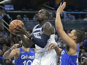 Minnesota Timberwolves forward Luol Deng, center, goes up for a shot between Orlando Magic guard Evan Fournier (10) and guard Isaiah Briscoe (13) during the first half of an NBA basketball game Thursday, Feb. 7, 2019, in Orlando, Fla.