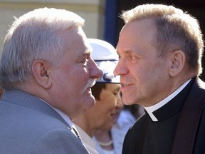 FILE - In this June 18, 2005 file photo former President Lech Walesa, left, welcomes father Henryk Jankowski at a party in Walesa's honor in Gdansk, Poland. Activists in Poland have pulled down a statue of Mgr. Henryk Jankowski after mounting allegations that he sexually abused minors.