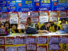 In this March 3, 2018, photo, people check on travel packages offered by travel agencies during the Guangzhou International Travel Fair in Guangzhou in south China's Guangdong province.