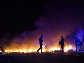 Police officers try to remove burning tires, set by demonstrators to block a highway in protest of the imprisonment of pro-independence political leaders during a general strike in Catalonia, Spain, Thursday, Feb. 21, 2019.