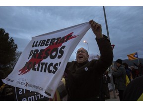 Demonstrators, one of them holding a banner reading in Catalan "freedom for the politics prisoners", protest outside the Brians II prison, in Barcelona, Spain, Friday, Feb.1, 2019. Catalan separatists, who have spent over a year in pre-trial jail for their part in Catalonia's illegal declaration of independence in October 2017 after holding a banned referendum, have been transferred from different Catalan prisons to Brians II center, ahead of a trial in the Spanish capital Madrid.