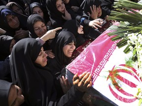 Mourners reach out to touch the caskets of those killed in a suicide car bombing that targeted members of Iran's powerful Revolutionary Guard in earlier in the week, killing at least 27 people, in Isfahan, Iran, Saturday, Feb. 16, 2019. The head of the Guard has threatened to retaliate against neighboring Saudi Arabia and United Arab Emirates over the bombing.