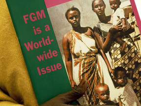 A survivor holds a book on female genital mutilation in London, England.