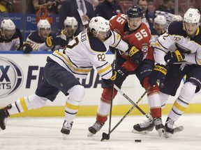 Buffalo Sabres defenseman Nathan Beaulieu, left, Florida Panthers center Henrik Borgstrom, center, and Sabres right wing Tage Thompson, right, compete for the puck during the first period of an NHL hockey game Tuesday, Feb. 19, 2019, in Sunrise, Fla.