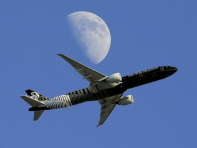 In this Aug. 23, 2015, file photo, an Air New Zealand passenger plane flies past the moon on its way to the Los Angeles International Airport from London, in Whittier, Calif.