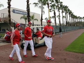 Philadelphia Phillies catcher Andrew Knapp, left, starting pitcher Aaron Nola, center, and relief pitcher Victor Arano, right, walk onto the field at the Philadelphia Phillies spring training baseball facility, Wednesday, Feb. 13, 2019, in Clearwater, Fla.