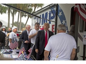 In an Aug. 24, 2016 photo, Republican presidential nominee Donald Trump meets supporters organizing voter registration and support for his campaign just before a rally at the Florida State Fairgrounds in Tampa, Fla. A woman is alleging in a new lawsuit filed Monday, Feb. 25, 2019, that Inside the RV seen here, Trump kissed a member of his campaign staff without consent. The woman, Alva Johnson, can be seen in the background of this photo wearing a Trump shirt and a hat on the left side of the frame.