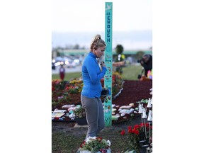 Kara Cannizzaro crosses herself after pausing at a memorial outside Marjory Stoneman Douglas High School during the one-year anniversary of the school shooting, Thursday, Feb. 14, 2019, in Parkland, Fla.