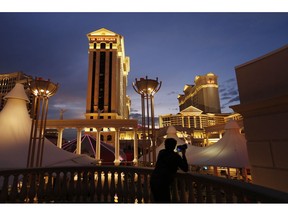 FILE - In this Jan. 12, 2015, file photo, a man takes pictures of Caesars Palace hotel and casino, in Las Vegas. Las Vegas is not worried about the competition from casinos in other states that for the first time Sunday, Feb. 3, 2019, will also offer football fans a chance to bet on the Super Bowl. The weekend is worth hundreds of millions of dollars to the city, which draws tens of thousands of people for the big game's weekend.