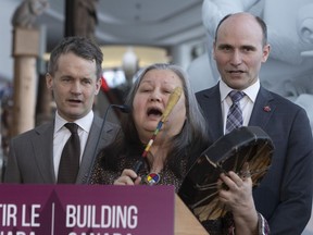 Seamus O'Regan Minister of Indigenous Services (left), Jean-Yves Duclos, Minister of Families, Children and Social Development,(right) take part in a ceremonial prayer with Indigenous elder Irene Compton before announcing investments to address Indigenous homelessness and housing, during a news conference in Gatineau, Que., across the river from Ottawa, Wednesday, February 20, 2019.THE CANADIAN PRESS/Fred Chartrand