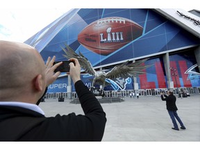 Jay Reid, left, takes a photo of Mercedes-Benz Stadium the evening before NFL football's Super Bowl, Saturday, Feb. 2, 2019, in Atlanta.