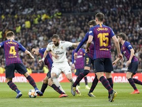 Real forward Karim Benzema fights for the ball with Barcelona players during the Copa del Rey semifinal second leg soccer match between Real Madrid and FC Barcelona at the Bernabeu stadium in Madrid, Spain, Wednesday Feb. 27, 2019.