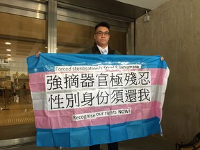 Transgender man, Henry Tse displays a banner outside a local court in Hong Kong Friday, Feb. 1, 2019. Hong Kong's High Court has refused to allow three transgender men, including Tse, to be recognised as males on their official identity cards because they have not undergone full sex-change operations. (Apple Daily via AP)