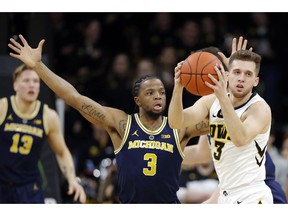 Iowa guard Jordan Bohannon grabs a loose ball in front of Michigan guard Zavier Simpson (3) during the first half of an NCAA college basketball game Friday, Feb. 1, 2019, in Iowa City, Iowa.