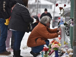 Mourners place a flower at the crosses outside of the Henry Pratt company in Aurora, Ill., on Sunday, Feb. 17, 2019, in memory of the five employees killed on Friday.