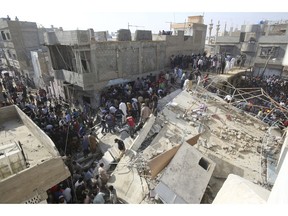 People gather near a collapsed building while rescue work is in progress in Karachi, Pakistan, Monday, Feb. 25, 2019. The small residential building collapsed as construction work was underway next to it in the city's Malir neighborhood.