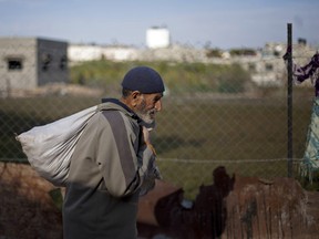 In this Dec. 25, 2013 file photo, a Palestinian man carries a sack of food as he walks in the Jabalya refugee camp in the northern Gaza Strip.