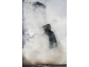 A pedestrian makes her way through some vehicle exhaust fog, caused by frigid temperatures, in downtown Winnipeg, Wednesday, Jan. 30, 2019. Manitoba Hydro says it has set an all-time record for electricity use during frigid weather.THE CANADIAN PRESS/John Woods